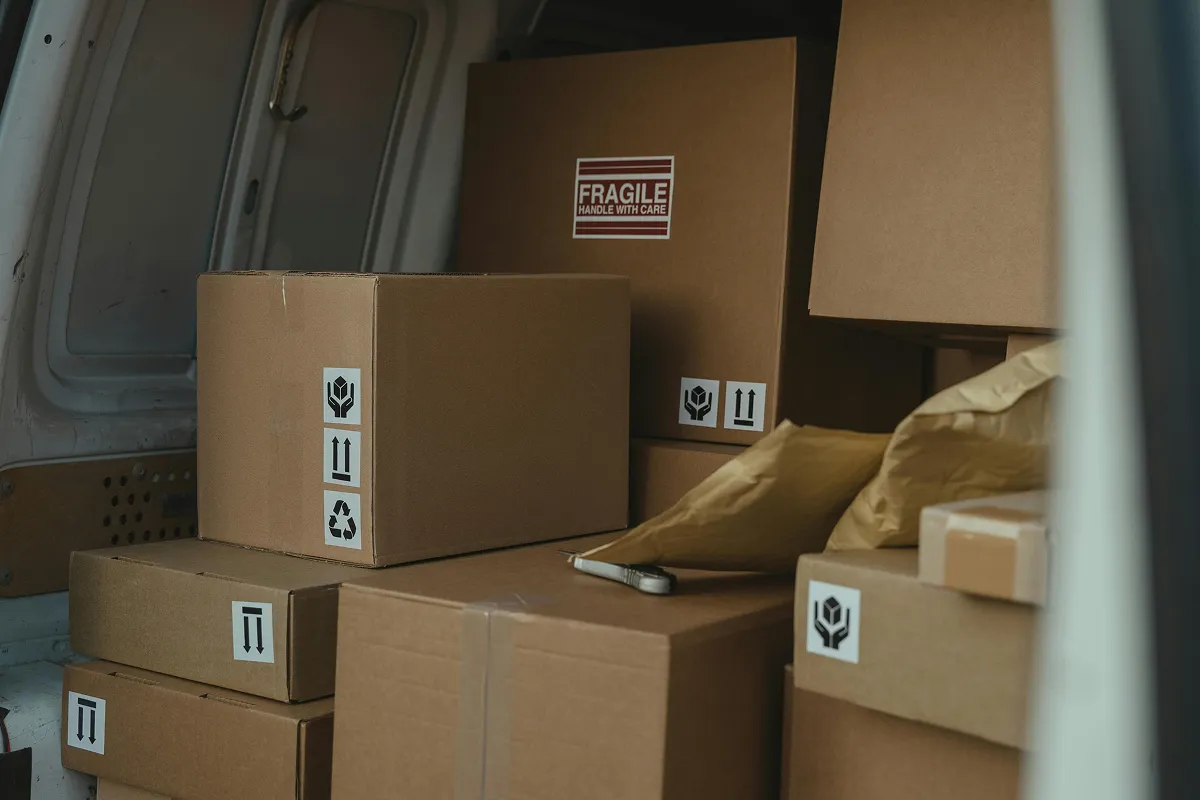 Cardboard boxes marked fragile stacked inside the back of a loaded moving van