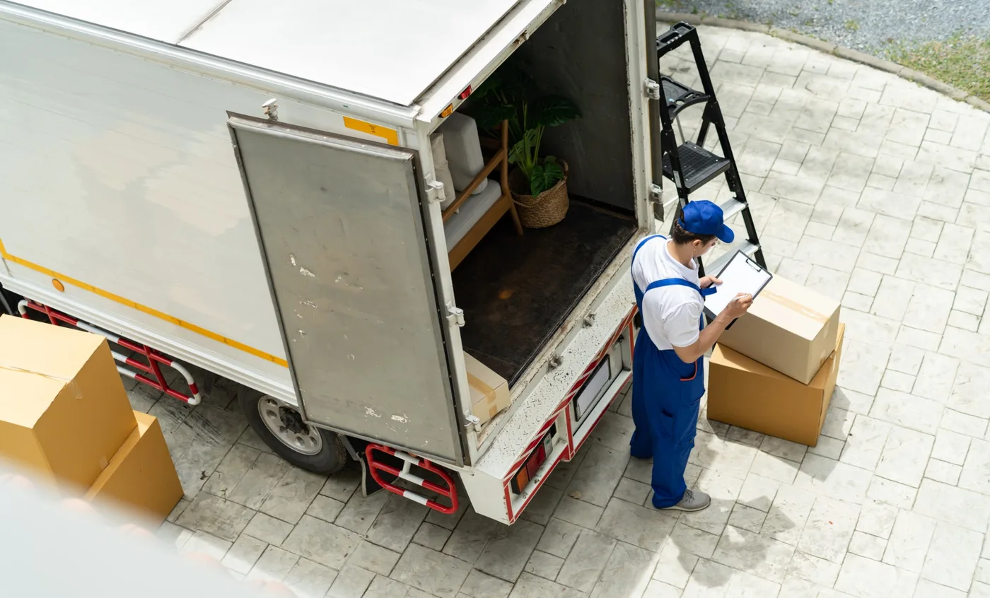 Overhead view of a mover with a clipboard checking boxes at the back of an open moving truck