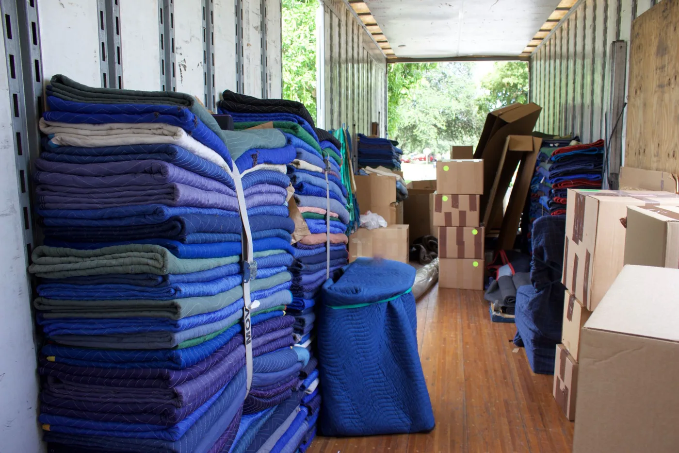Stacks of folded moving blankets and cardboard boxes inside a moving truck