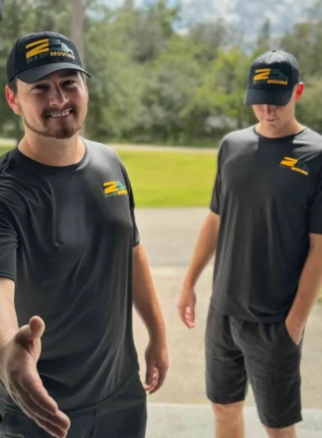 Two In A Zip Moving crew members in branded caps and shirts, one reaching out to shake hands